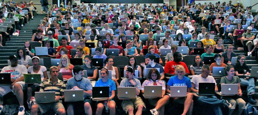 Students sitting with laptops in a lecture style classroom