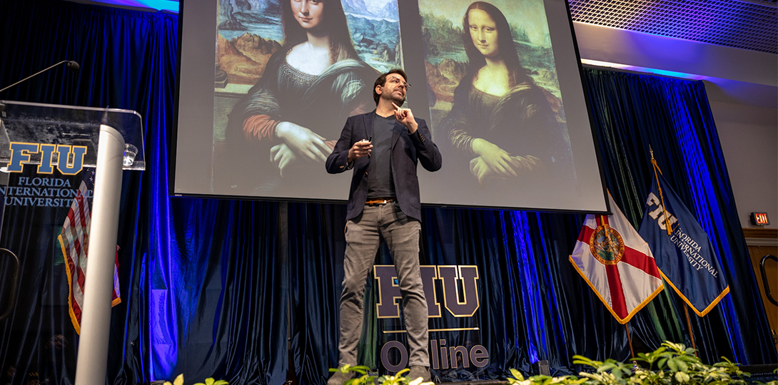 Keynote speaker presenting on stage with two version of the mona lisa depicted on the screen behind him