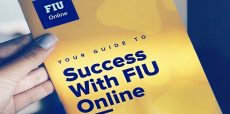 Hand holding a booklet with FIU Online logo; cover reads Your Guide to Success with FIU Online